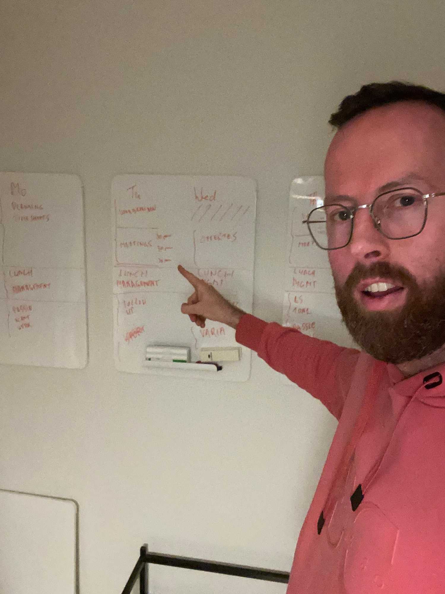 Titanology CEO Stefaan points to a whiteboard with an updated ideal time schedule for CEO Roel