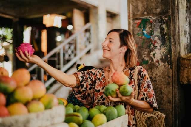 Ilse Cuvelier, owner of Illiemangaro, smiling and holding fruits in both hands
